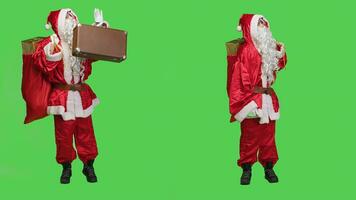 Santa claus hitchhiking with suitcase and presents in red sack, spreading christmas eve spirit and positivity. Person acting like saint nick carrying gifts and briefcase to deliver toys. photo