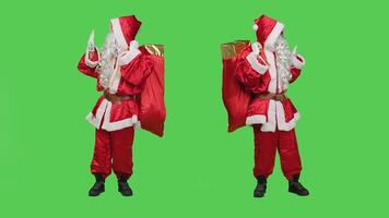 Young adult pushing something aside and expressing rejection, acting like santa claus in red costume with hat. Man portraying saint nick to push objects to left or right sides, greenscreen. photo