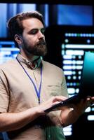 Expert in server room with advanced data storage infrastructure storing massive datasets, supporting intensive operations requiring IT equipment to run at high power densities photo