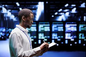 Adept supervisor overseeing server hub using renewable sources to minimize consumption and reduce overall facility carbon footprint. African american technician working in eco friendly data center photo