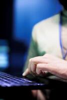 Close up of engineer in data center using laptop to work with essential datasets for training machine learning models that power artificial intelligence systems necessitating high processing power photo