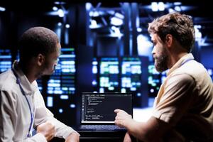 IT developers coworkers writing script code in server room on laptop terminal. Teamworking programmers doing maintenance work in technologically advanced data center updating racks software photo