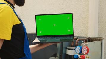 Technician ordering new components on chroma key laptop for damaged air conditioner after finishing investigation. Mechanic looking online for condenser replacement parts, comissioned by customer photo