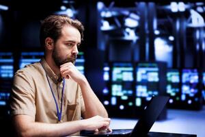 Puzzled employee thinking how to best improve supercomputers helping businesses manage databases, host websites and store files. Worker auditing server hub devices used for high performance computing photo