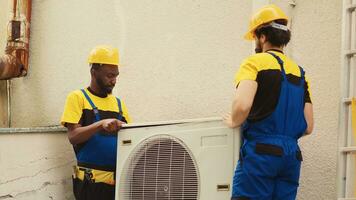 Teamworking licensed servicemen starting work on faulty hvac system, taking apart condenser coil panel. Qualified electricians disassembling air conditioner to check for improper wiring photo