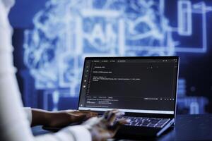 Qualified technician updates neural networks made up of interconnected nodes, writing intricate binary code scripts on laptop. Skilled expert uses programming to upgrade AI simulation model photo