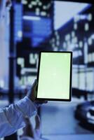 Person having fun walking around city at night, scrolling on social media using mockup tablet, close up. Citizen using green screen device while strolling in empty metropolitan setting photo