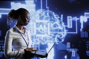 Tech support uses laptop to develop artificial intelligence neural networks nodes modeled after human brain. Data center worker setting up AI machine learning accurately making predictions using data photo