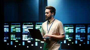 Professional doing annual system investigation, adding data on laptop of needed refurbishing in server clusters housing advanced data storage equipment supporting important IT workloads photo