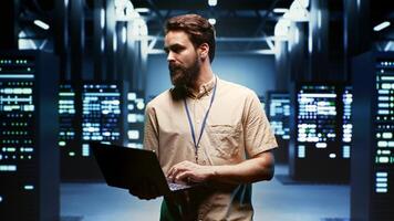 Engineer using laptop to monitor energy consumption across server components and distributors. Expert ensuring data center sensors for temperature and humidity are functioning optimally photo
