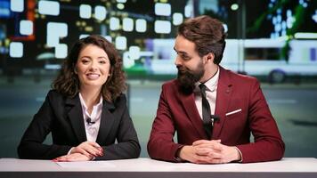 Media team hosting night talk show, discussing about international daily events in news studio. Two journalists addressing all breaking news topics live on television network. photo