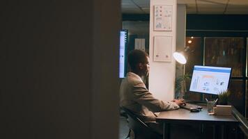 Revealing shot of employees checking company figures, postings and documents for accuracy during nighshift. Staff member working overnight, analyzing stored computerized financial information photo