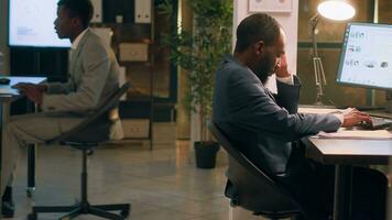 Overworked african american employee asleep in desk chair during nightshift, being woken up by fresh coworker. Joyful colleague playing jokes on sleepy businessman, scaring him photo