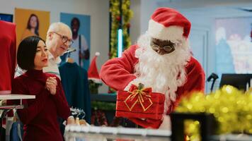 Worker wearing Santa Claus outfit in xmas ornate clothing store, inviting customers to participate in Christmas raffle competition in order to win promotional prize during festive holiday season photo