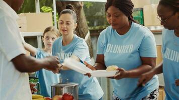 Homeless and refugee shelter receives donations and distributes to needy with help from humanitarian aid organization. At non-profit food bank, female volunteers share free meals to less privileged. photo