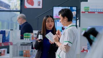 Experienced healthcare professional in apothecary helping customer with medical suggestions. Client wishing to purchase supplements and vitamins, asking druggist for recommendations photo