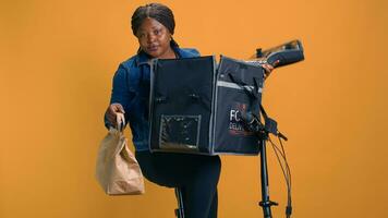 africano americano mujer agarrando para llevar desde comida entrega bolso para persona en local vecindario. sonriente mensajero Proporcionar rápido y de confianza cliente Servicio por dando Fresco eliminar comida a cliente. foto