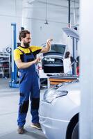 Serviceman in repair shop using augmented reality holograms to check car condition during maintenance. Garage employee using futuristic AR technology to examine out of order vehicle photo