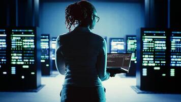 Dilligent worker running code on laptop, troubleshooting and upgrading high tech workplace infrastructure designed to accommodate server components, networking systems and storage arrays photo
