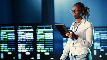 African american woman walking through data center systems providing processing resources for different workloads. Admin diagnosing server hub equipment tasked with solving complex operations photo