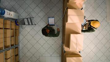 Top down view of logistics coordinators examining cardboard box parcels for defects in warehouse. Storage room coworkers making sure stocks and inventory are well organized photo