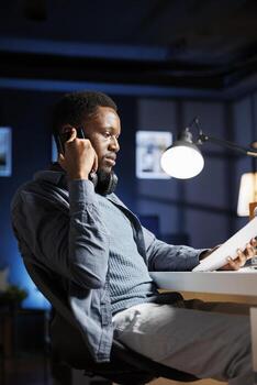 Financial investor analyzing capital balance report papers at home, doing remote work and talking on phone call with CEO. Expert using monthly revenue accounting files to increase earnings. photo