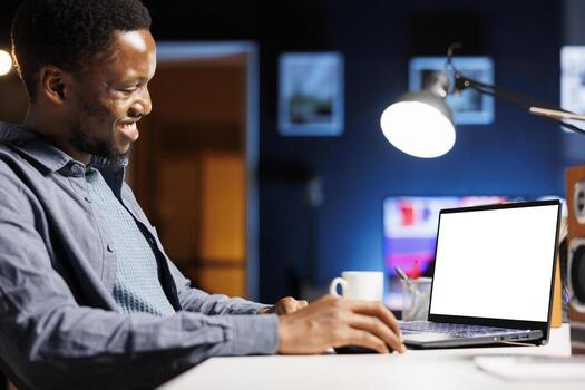 While telecommuting, self employed individual glances at empty layout on laptop and builds his abilities at home. Employee enjoying self education online class package, personal program. photo