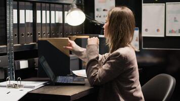 caucásico mujer policía inspeccionando evidencia, revisando registros, y utilizando tecnología en un bien organizado oficina espacio. dedicado investigador análisis testigo declaraciones y registros a resolver delito. foto