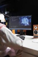 Arab guy works on a computer, utilizing AI, coding, and cyber security. He monitors data on a desktop pc screen, controlling a powerful cloud-based system. Over-the-shoulder shot. photo