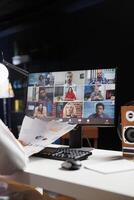 Selective focus on the desktop screen displaying group of people participating in a video conference. Detailed image of professional adults discussing their research in an online meeting. photo