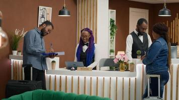 Travellers signing documents and finishing check in process at front desk reception, hotel concierge workers ensuring easy registration. Receptionist providing great service to guests on trip. photo