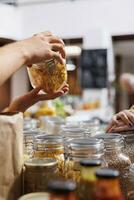 Storekeeper helping client looking for eco friendly cereals in local neighborhood shop. Seller offering customer information about product in sustainable zero waste supermarket, close up photo