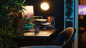 Revealing shot of computer screens showing running animation rendering in dimly lit empty home interior. 3D renders on digital displays on cozy apartment living room work desk photo