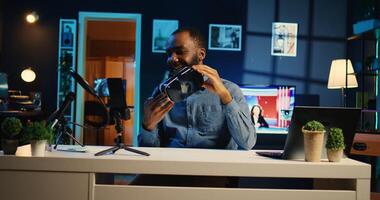 Tech influencer filming sponsored branded content, unboxing newly released VR glasses product. Cheerful content creator presents virtual reality headset parameters to subscribers photo