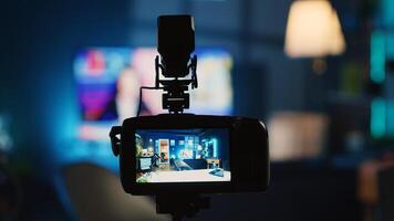 Extreme close up shot of camera on tripod used by online star in dimly lit home studio to film video for online platforms. Recording device in empty room used by influencer to capture footage photo