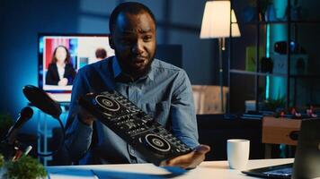 African american content creator filming technology review of newly released DJ controller, unpacking it and presenting specifications to audience. Influencer showing turntables to fans photo