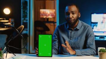 Content creator films chroma key tablet video review for tech enthusiasts. Viral online star hosts technology internet show, unboxing green screen digital device, focus on product photo