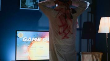 Gamer upset at seeing game over message on TV screen playing arcade space shooter videogame. Man spending time at home on gaming system, frustrated after losing esports competition photo