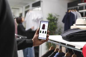 In a contemperory boutique, a caucasian customer holds a digital device. Stylish male shopper using modern technology to browse for fashionable merchandise in a clothing store. photo