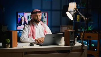 Arab job candidate remotely being interviewed by human resources team while at home. Muslim man getting his credentials checked during online video conference meeting before being employed photo