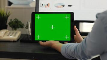 Woman checking greenscreen on tablet in creative agency coworking space, looking at chromakey display with isolated mockup on mobile gadget layout. Employee holding mockup device. photo