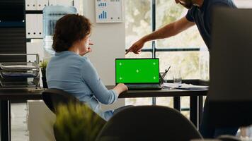 Startup team checking greenscreen app on laptop layout, brainstorming new budget ideas and working on business operations. Colleagues discussing at desk, isolated chromakey display. photo