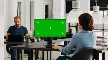 Employee using computer at desk, monitor running greenscreen template in business agency office. Company specialist looking at isolated chromakey display with mockup copyspace, digital network. photo