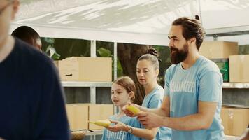 Male and female volunteers share food and provisions with less privileged during charity food drive. Voluntary individuals offer hunger relief to homeless people demonstrating spirit of volunteering. photo