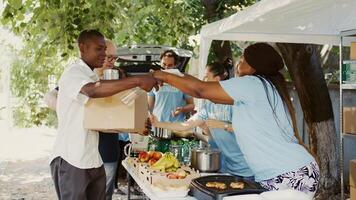 Diverse group distributing contribution boxes to those in need at a homeless and refugee shelter. Multiracial volunteers share essentials and provide support through a non-profit food bank. Handheld. photo