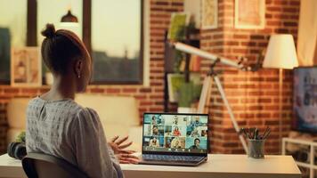 African american girl on videocall doing briefing meeting for new research plan to solve online tasks. Woman waving at videoconference webcam, using laptop at home. Tripod shot. photo