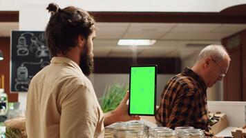 Man using isolated screen smartphone in zero waste supermarket to check ingredients for healthy recipe. Client in local grocery shop uses mockup mobile phone while shopping for organic veggies photo