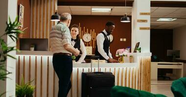 Old traveller ringing service bell in lobby, calling for hotel concierge assistance with check in registration forms. Senior man wanting to start vacation and see room after long flight. photo