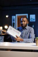 BIPOC content creator filming tech tutorial on how to repair laptop, presenting internal components. Technology guru in home studio teaching subscribers to fix notebook device photo