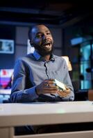 Influencer in studio using camera to capture live broadcast, reviewing mini RGB lights. BIPOC online show host filming electronics haul, presenting wireless LED lighting device to viewers photo